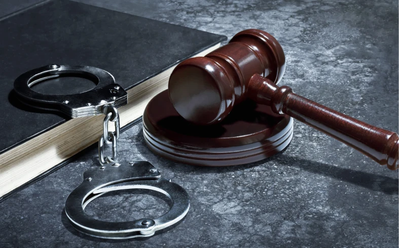 Gavel, handcuffs, and book on table.